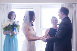 couple holing hands looking at officiant