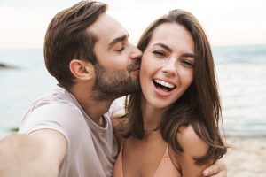 happy young couple with man kissing woman's cheek