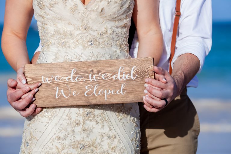 couple holding sign that says "we do we did we eloped"