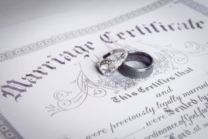 marriage certificate with bride and groom wedding rings on top