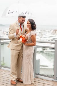 couple smiling on wedding day under an umbrella