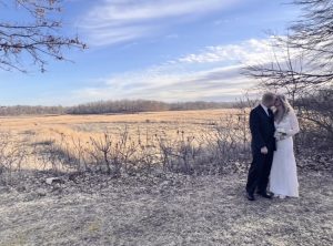 married couple kissing with beautiful backdrop of nature after drive thru wedding