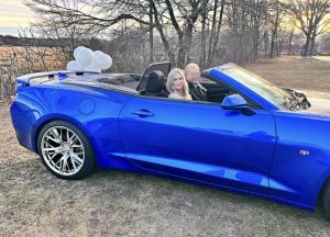 married couple in blue convertible after drive thru wedding