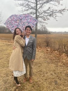 couple smiling under umbrella after drive-thru wedding