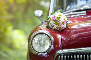 close up of a red car with a bouquet of wedding flowers on it