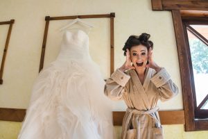 bride in a robe stressed while her wedding gown hangs up behind her