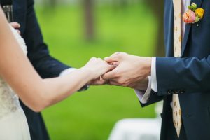 wedding officiant holding the hands of bride and groom