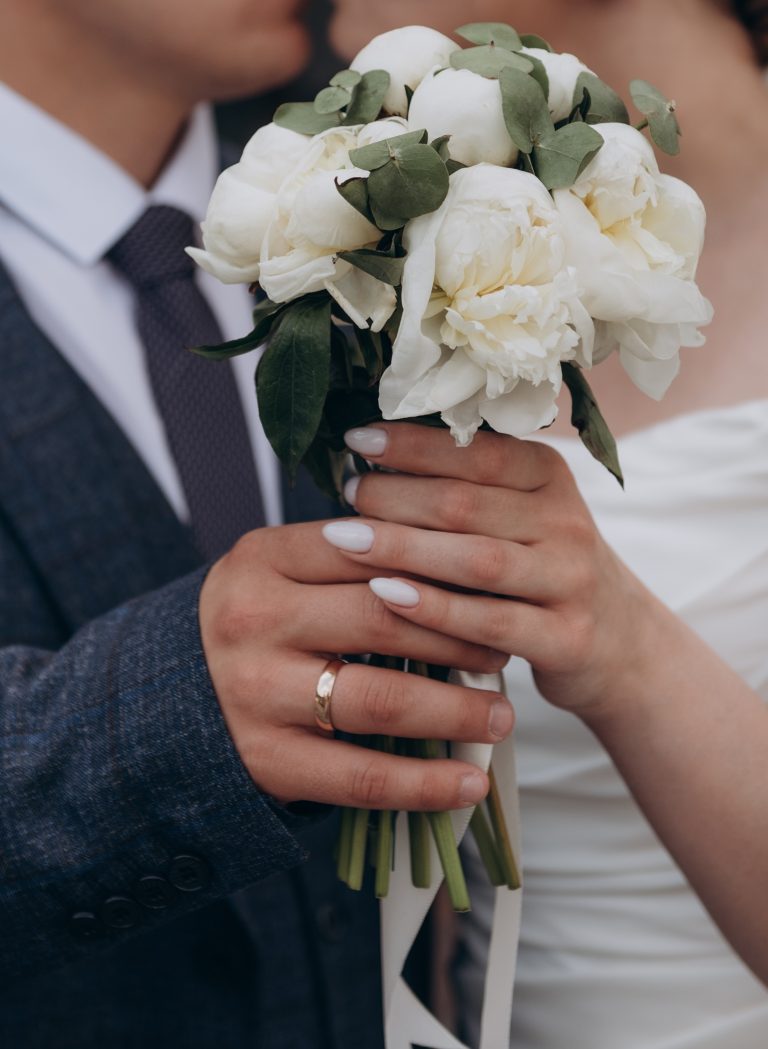 The bride in a white wedding dress is holding a bouquet of white flowers - peonies.. Wedding. Bride and groom. Wedding Dress